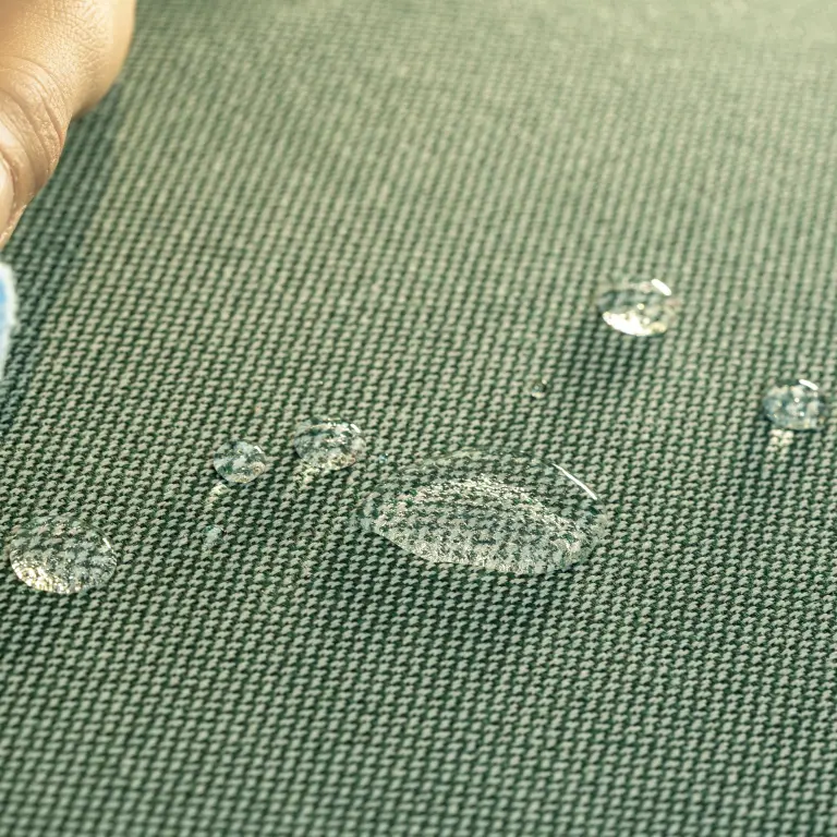 Close-up of a hand wiping spills from Vescom Clint, a 100% recycled polyester fabric with a hydrophobic finish.