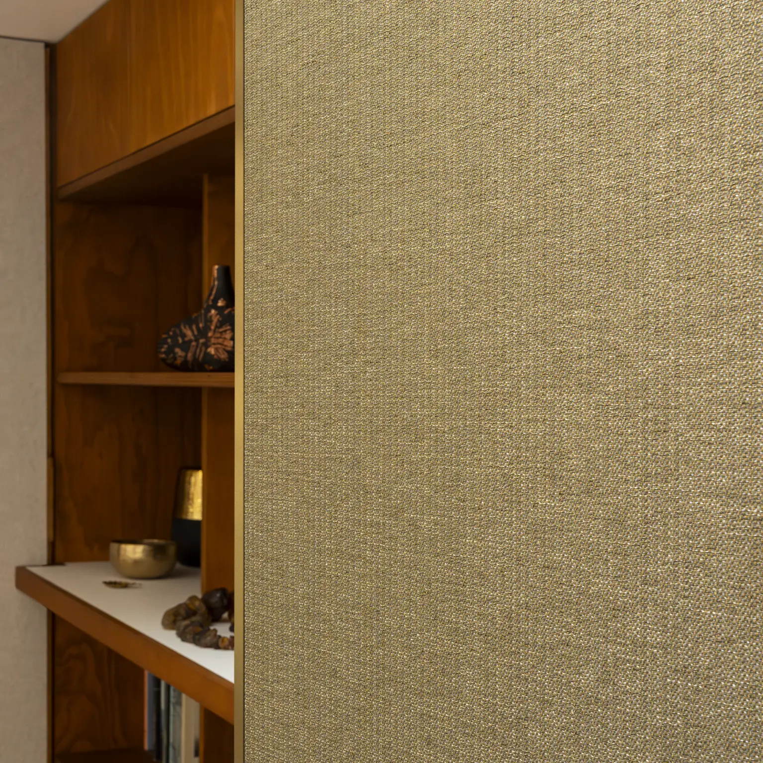 Close-up of Vescom Amber woven textile wallcovering with warm gold tone and irregular melange texture beside wooden shelving