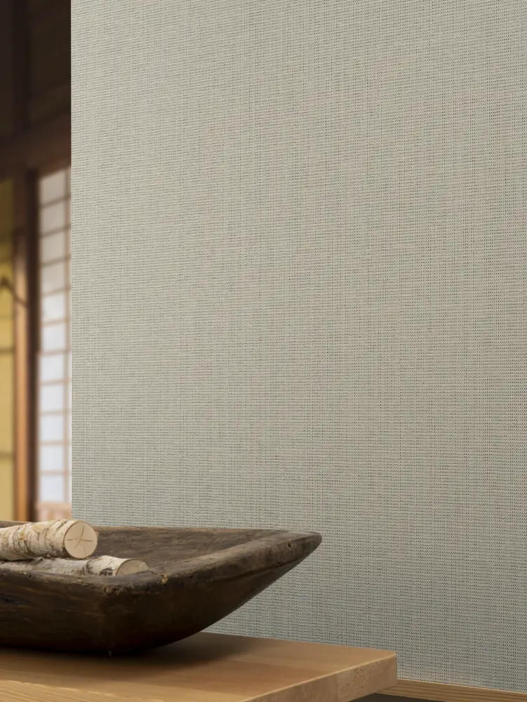 Vescom Birch woven textile wallcovering with subtle slub texture and architectural grid behind a wooden bowl on a table